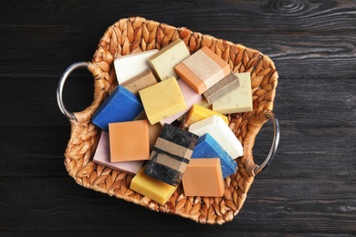 Photo of Many different handmade soap bars in wicker basket on table, top view