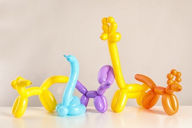 Photo of Animal figures made of modelling balloons on table against color background