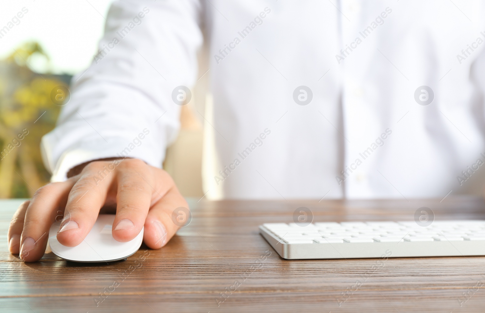 Photo of Man using computer mouse and keyboard at table, closeup