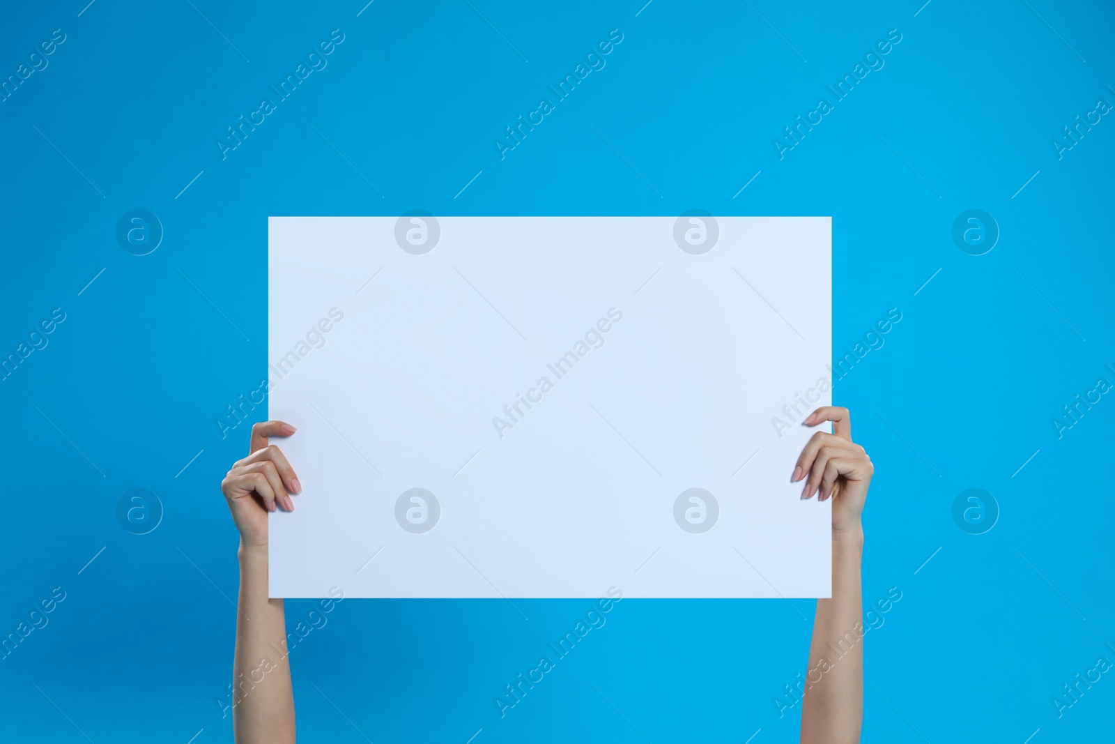 Photo of Woman holding blank poster on blue background, closeup