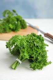 Photo of Fresh green parsley on wooden table against color background, space for text