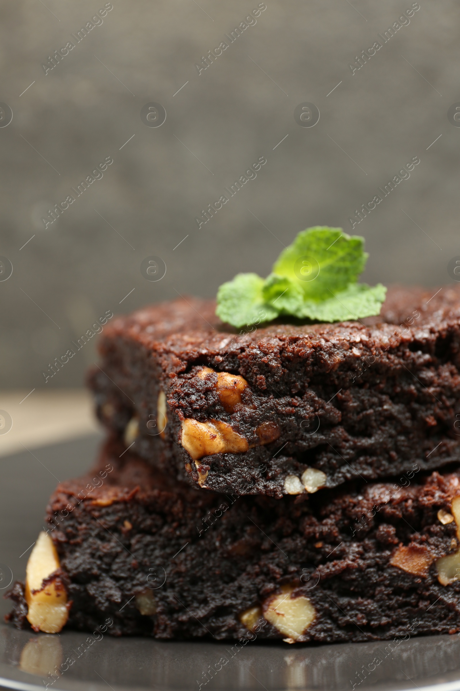 Photo of Delicious brownies with nuts and mint on grey plate, closeup