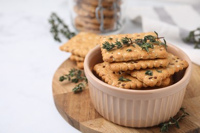 Cereal crackers with flax, sesame seeds and thyme in bowl on light table, closeup. Space for text