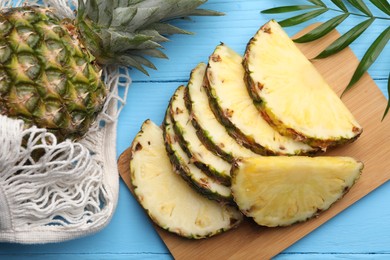Photo of Whole and cut ripe pineapples on light blue wooden table, flat lay
