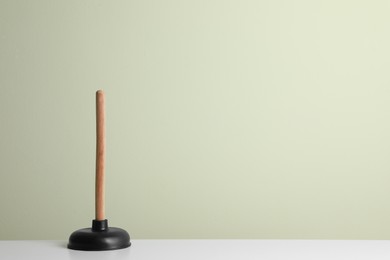 Photo of Plunger on white table against light background. Space for text