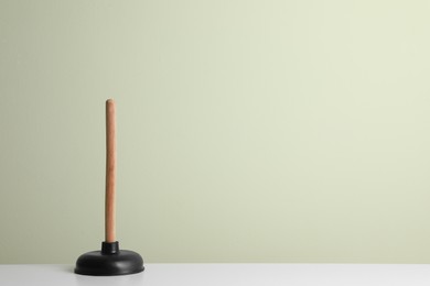 Plunger on white table against light background. Space for text