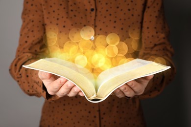 Image of Woman reading Bible, closeup view. Bokeh effect