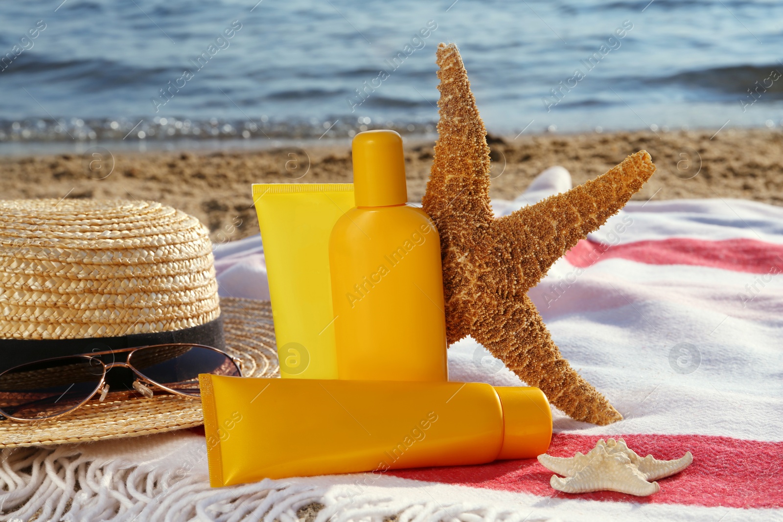 Photo of Sun protection products and beach accessories on blanket near sea