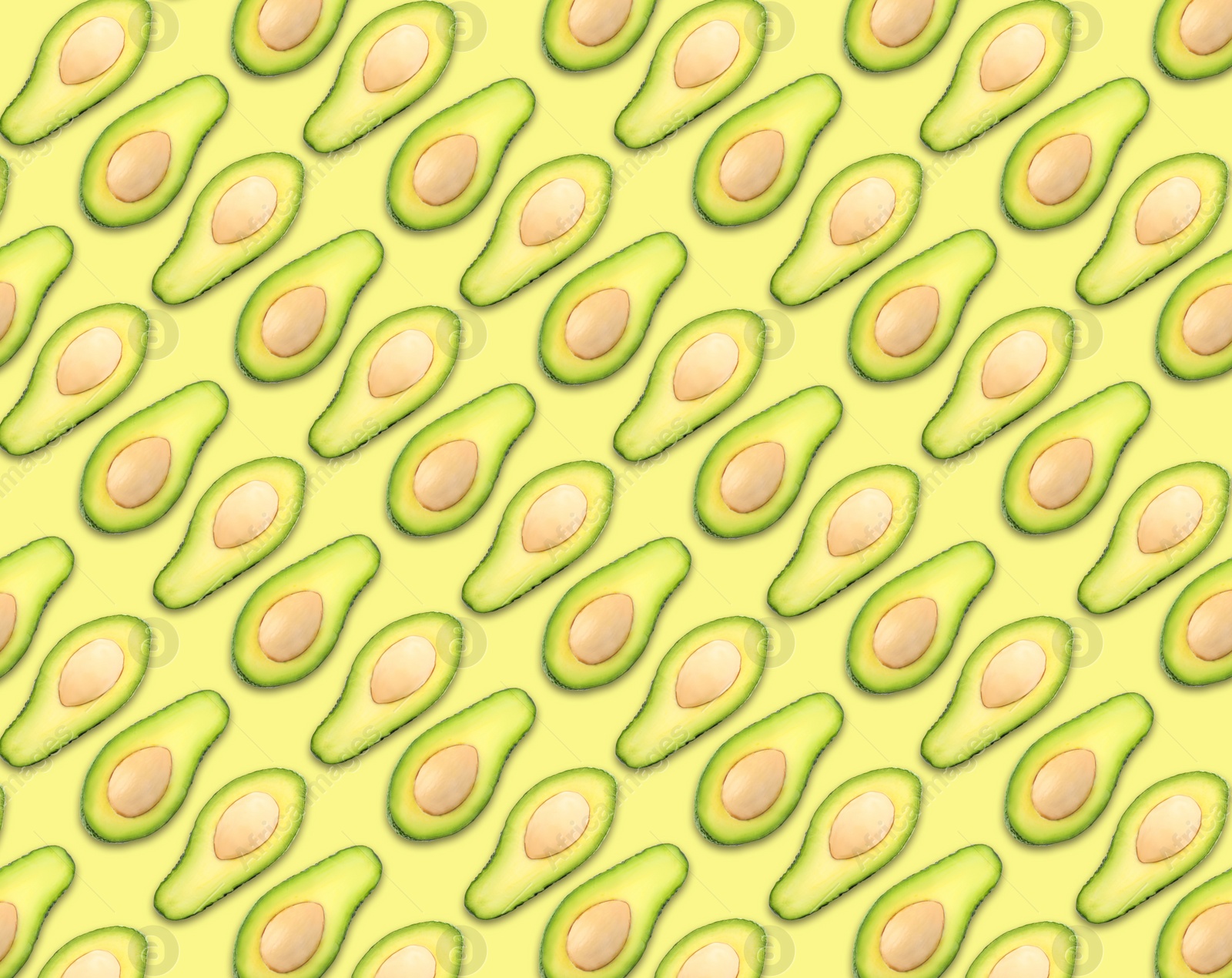 Image of Pattern of avocado halves on pale yellow background