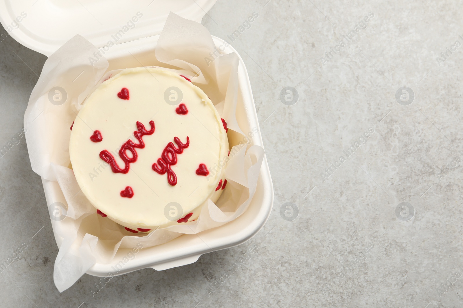 Photo of Bento cake with Love You text in takeaway box on light grey table, top view. Space for text. St. Valentine's day surprise