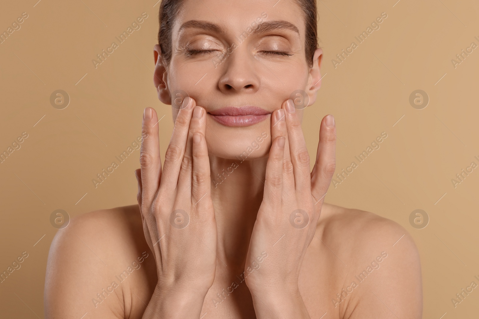 Photo of Woman massaging her face on beige background