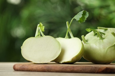 Photo of Whole and cut kohlrabi plants on wooden table, closeup