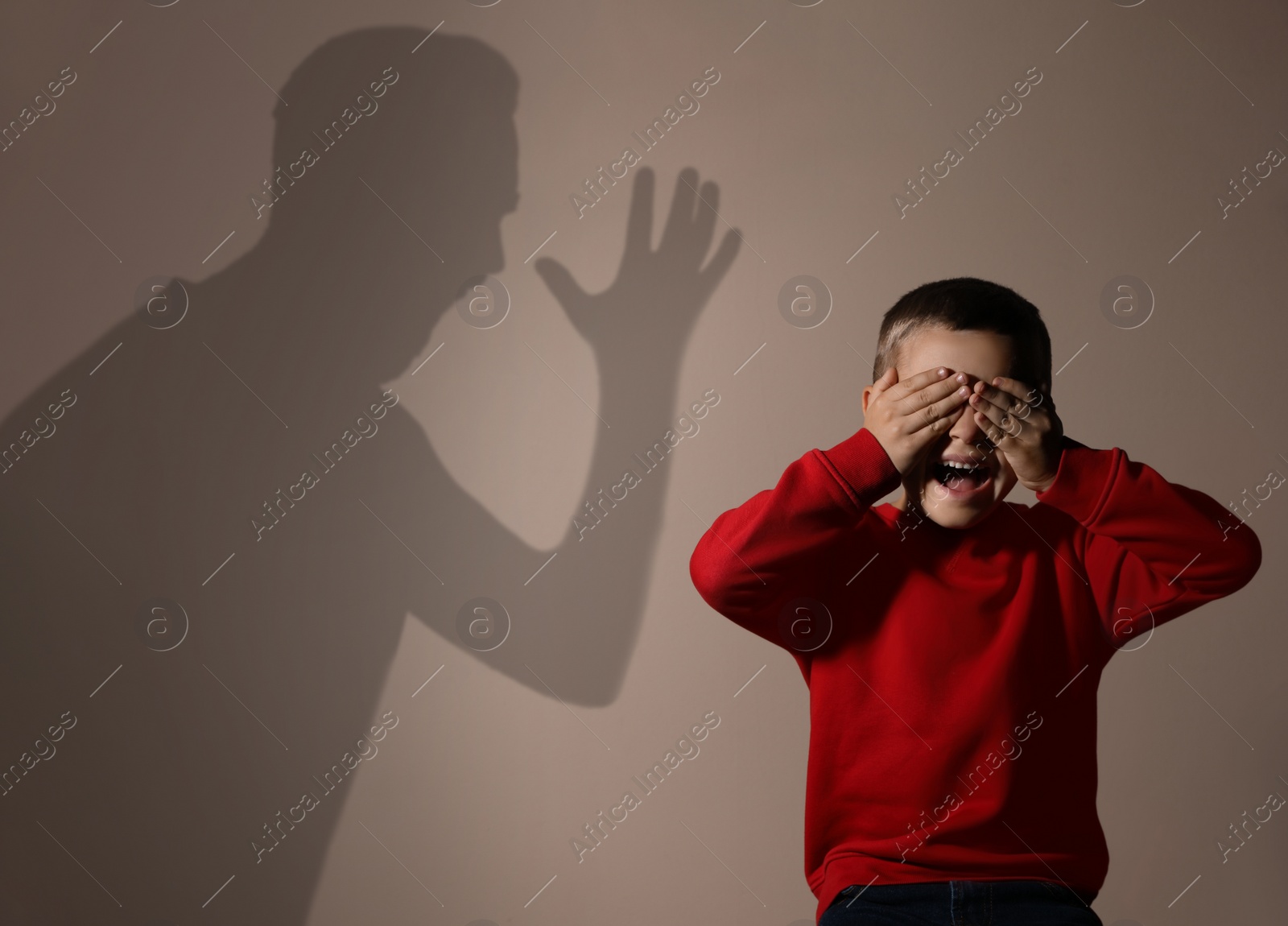 Image of Child abuse. Father yelling at his son. Shadow of man on wall