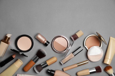 Photo of Face powders and other makeup products on grey background, flat lay. Space for text
