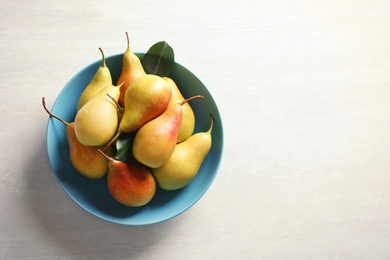 Plate with ripe pears on light background, top view. Space for text