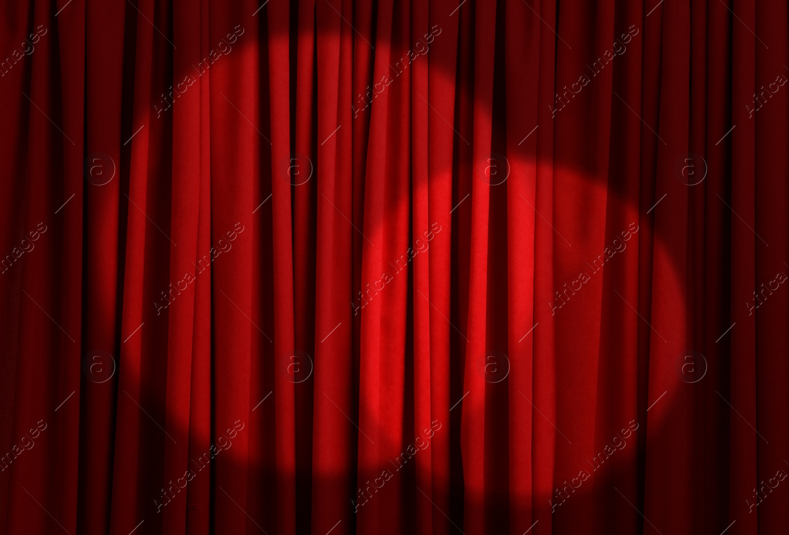 Image of Spotlights illuminating closed red stage curtains. Start of performance 