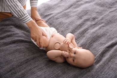 Photo of Young woman massaging cute little baby on blanket