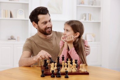 Photo of Father teaching his daughter to play chess at home