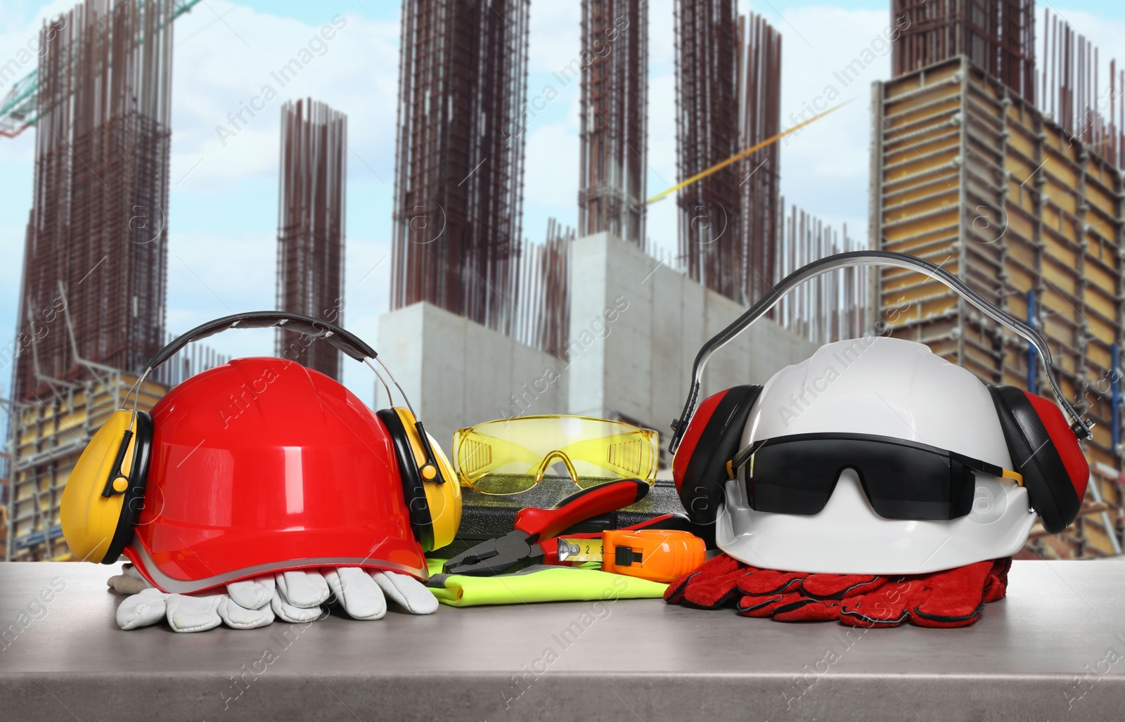 Image of Safety equipment and tools on grey stone surface and blurred view of construction site