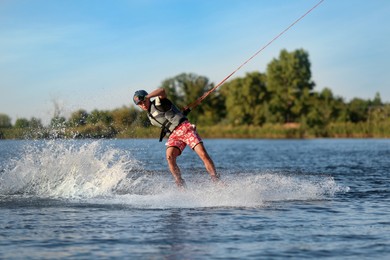 Photo of Teenage boy wakeboarding on river. Extreme water sport