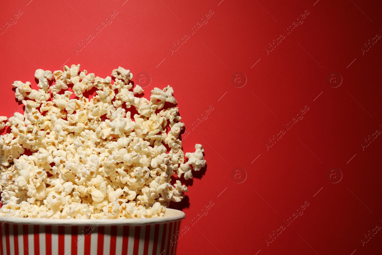 Photo of Delicious popcorn on red background, top view. Space for text