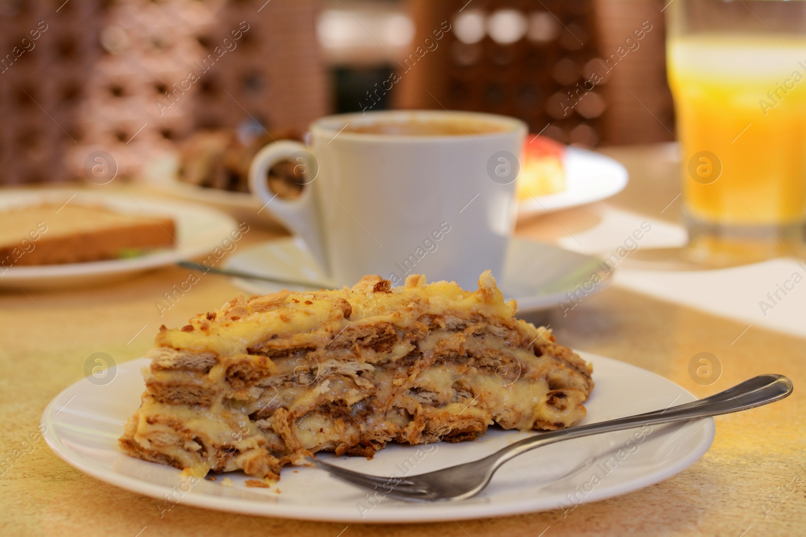 Photo of Piece of delicious cake and coffee on beige table in cafe, closeup