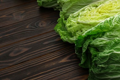 Photo of Fresh ripe Chinese cabbages on wooden table, closeup. Space for text