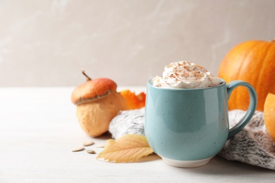 Photo of Cup with tasty pumpkin spice latte on light table. Space for text