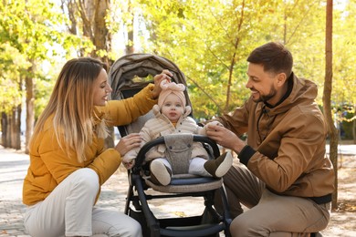 Photo of Happy parents with their baby in stroller at park on sunny day