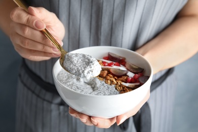 Photo of Young woman eating tasty chia seed pudding, closeup