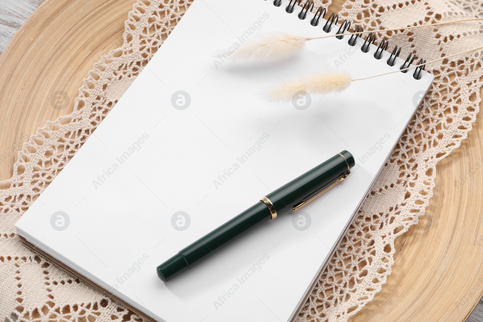 Photo of Guest list. Notebook, pen, spikelets and lace ribbon on wooden board, above view