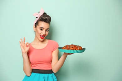 Photo of Funny young housewife with homemade pastry on color background