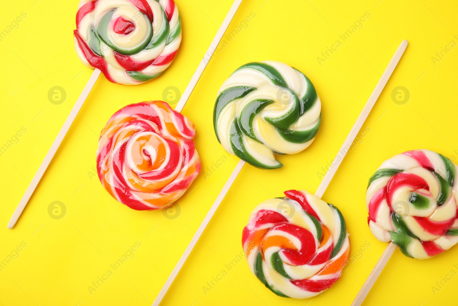 Photo of Many colorful lollipops on yellow background, flat lay