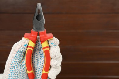 Photo of Man with combination pliers on wooden background, closeup. Space for text