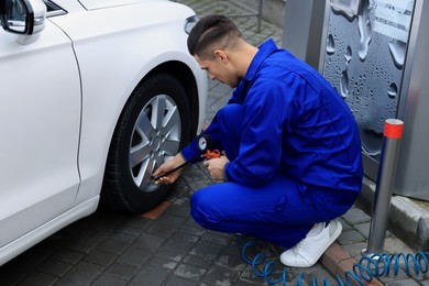 Photo of Professional mechanic inflating tire at car service