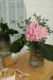 Beautiful pink hortensia flowers in vase on dressing table indoors