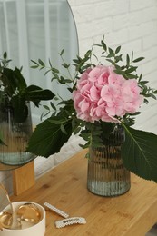 Photo of Beautiful pink hortensia flowers in vase on dressing table indoors