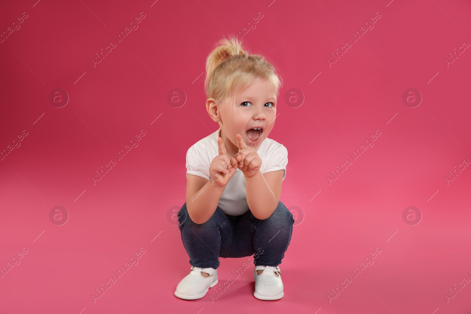 Photo of Portrait of emotional little girl on pink background