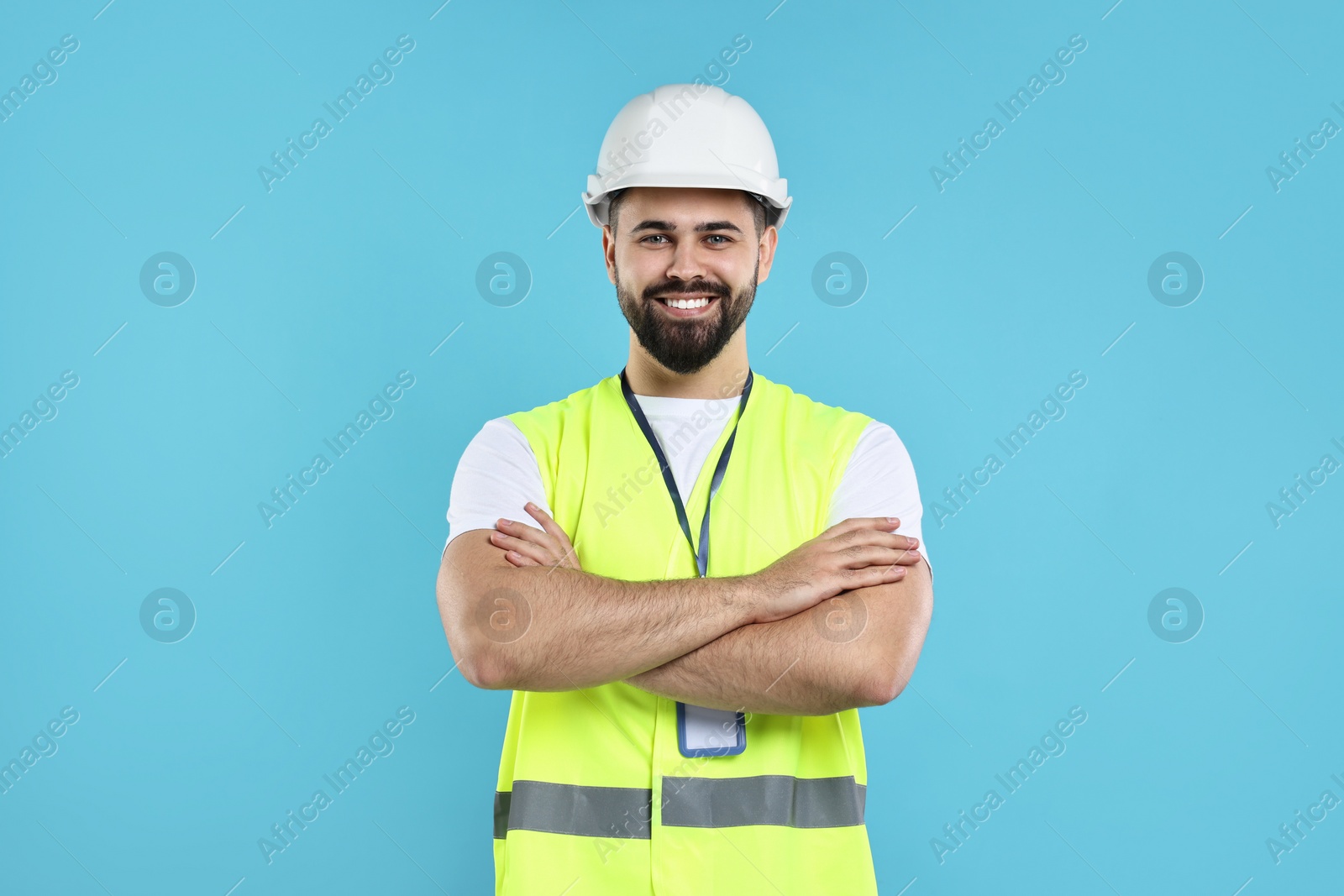 Photo of Engineer with hard hat and badge on light blue background