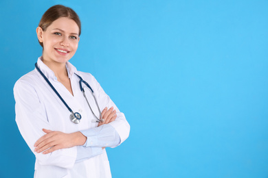 Photo of Portrait of young doctor with stethoscope on blue background, space for text