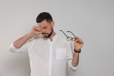 Man suffering from eyestrain on light background
