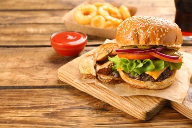 Photo of Tasty burger with potato wedges served on wooden table, space for text. Fast food