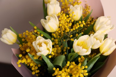 Bouquet of beautiful spring flowers near beige wall, closeup