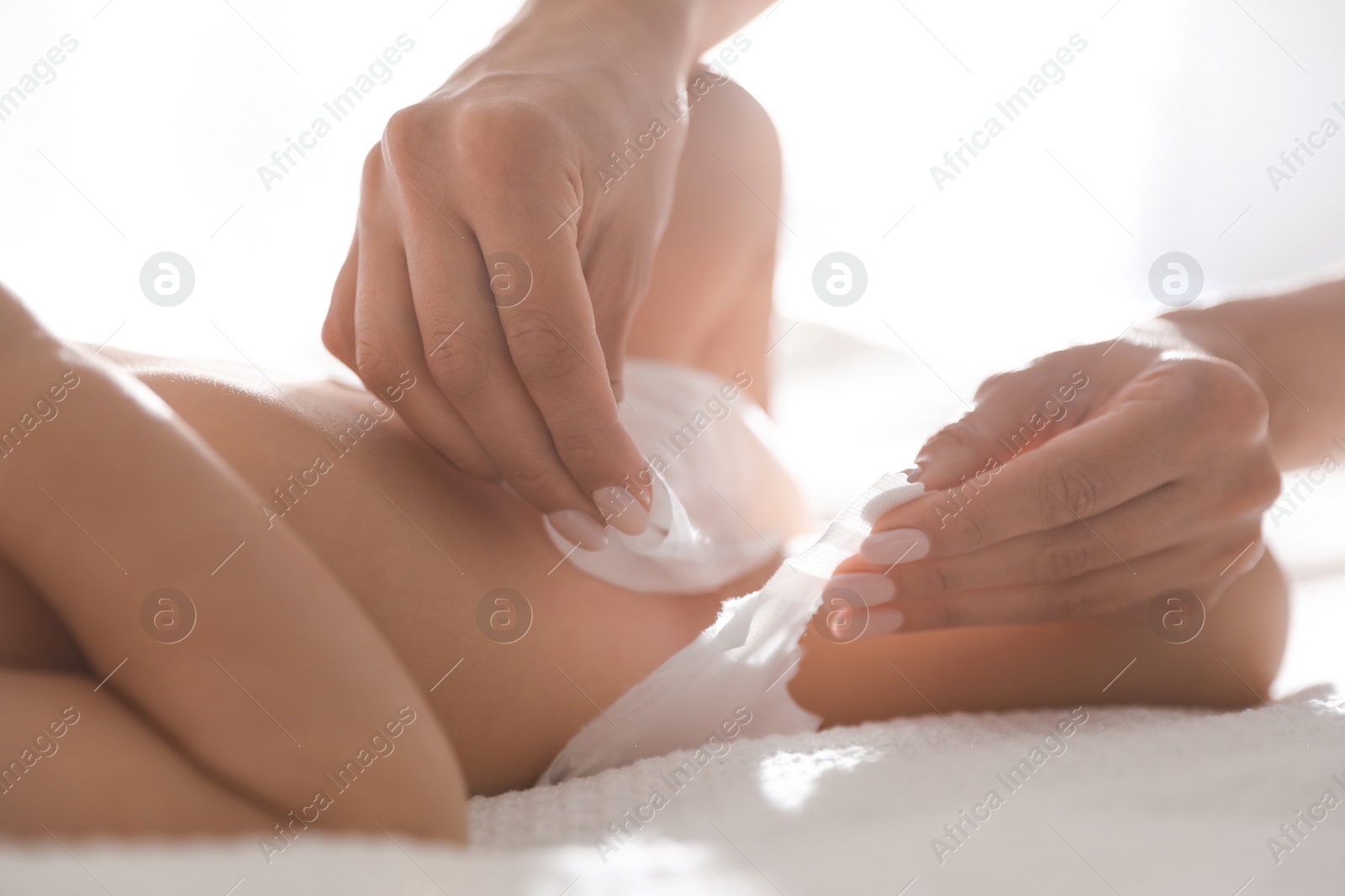 Photo of Mother changing baby's diaper on bed at home, closeup