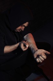 Photo of Addicted man taking drugs on dark background
