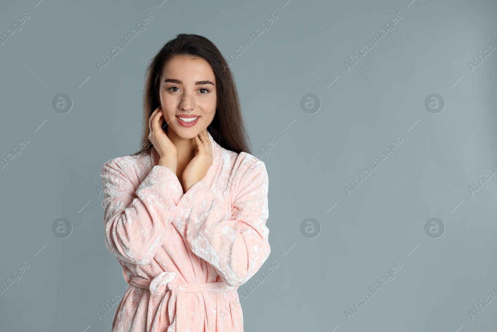 Photo of Beautiful young woman in bathrobe on grey background. Space for text