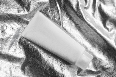 Photo of Tube with face cleansing product on silver background, top view