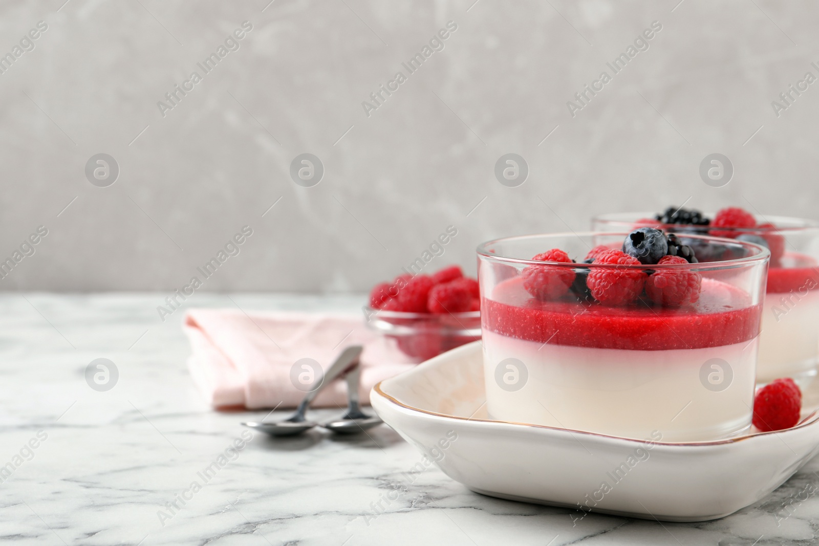 Photo of Delicious panna cotta with fruit coulis and fresh berries served on white marble table. Space for text