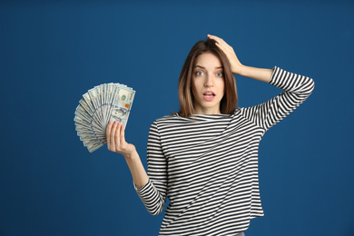 Photo of Emotional young woman with cash money on blue background