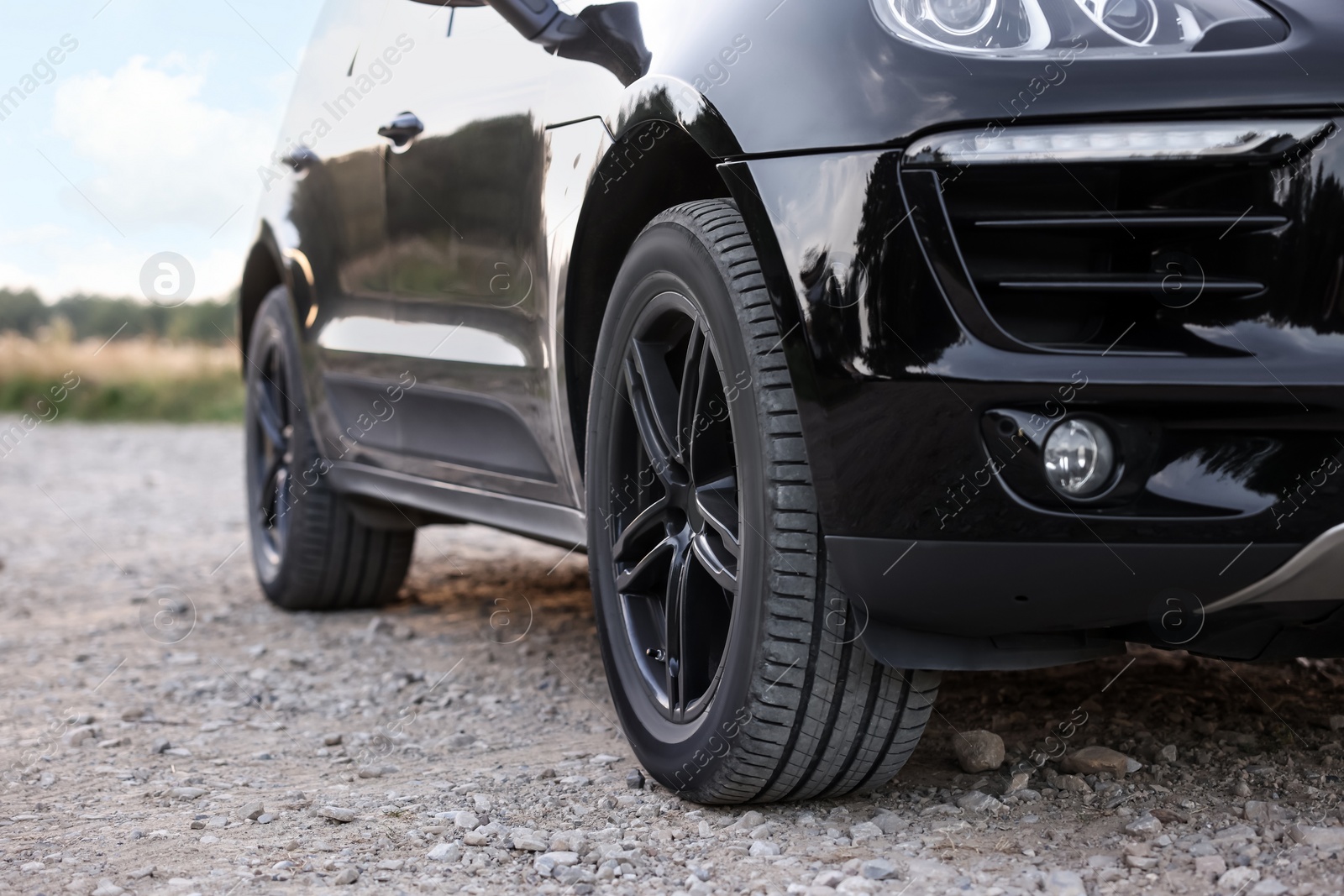 Photo of Modern black car parked on rubble road outdoors